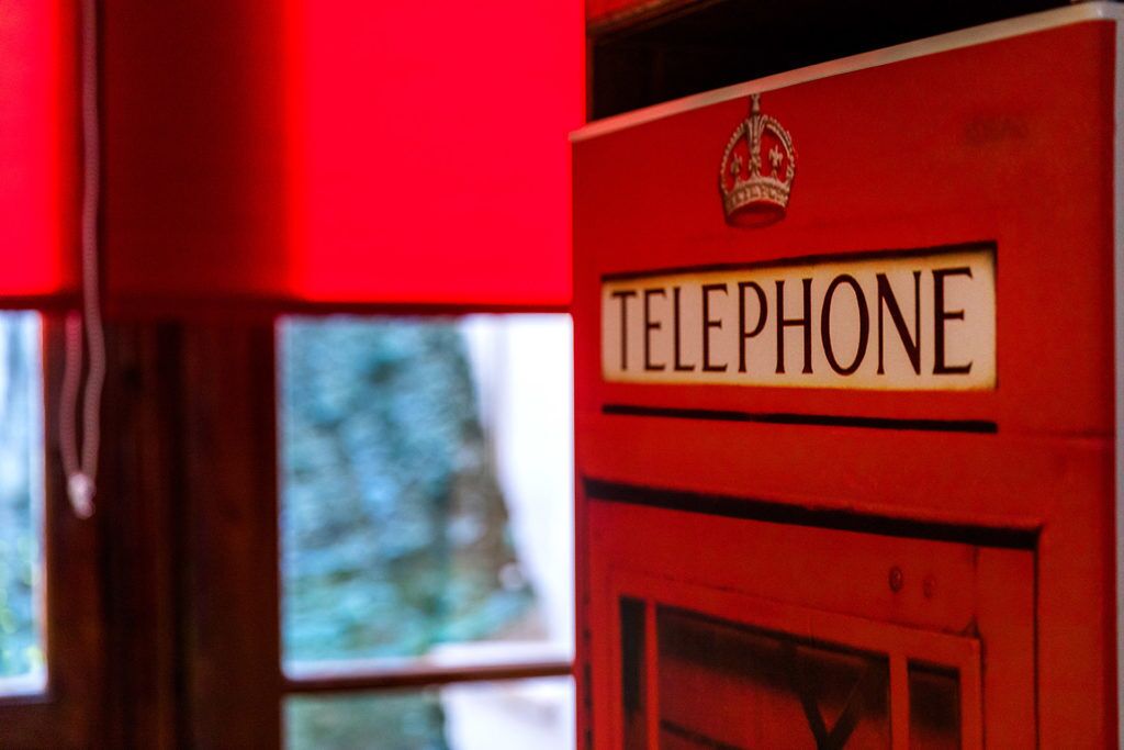 A red telephone booth with a crown emblem, indicating a historical or themed setting.