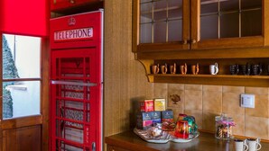 A kitchen with wooden cabinets, a red telephone booth, and various kitchen items on the counter. - Minotavros Cozy (Heraklion)