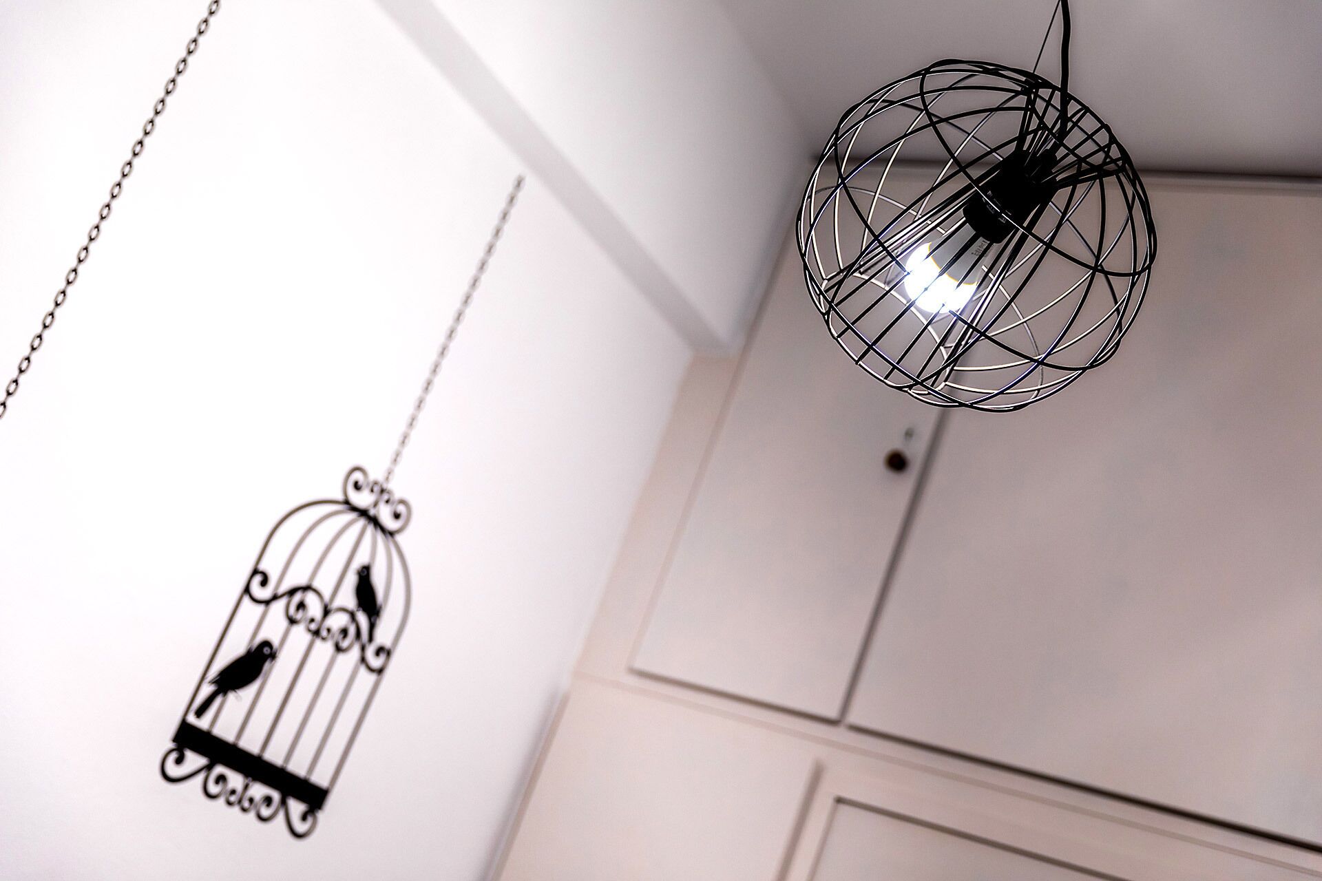Una habitación con una lámpara colgante y una jaula decorativa.