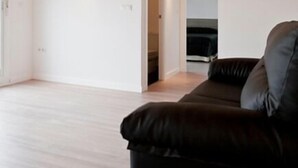 A modern living room with a wooden ceiling, a black leather sofa, and a white wall. - Hostal Central (Fuente Alamo)