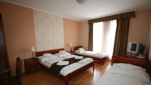Habitación de hotel con dos camas, un escritorio, una silla, un televisor y una ventana con cortinas.