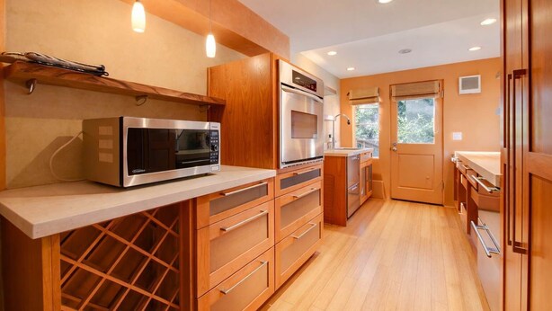 Eine moderne Küche mit integrierten Geräten, Holzschränken und einem Weinkühlschrank.