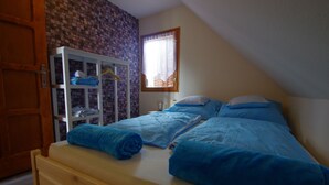Une chambre à coucher avec un lit en bois, une armoire et une fenêtre avec un rideau.