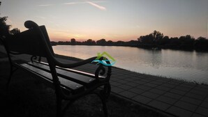 Un banc au bord d’une étendue d’eau paisible, au coucher du soleil.