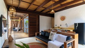A modern living room with a sofa, a dining table, and a kitchen area. - Villa Kandui Boutique Hotel (Maraú)