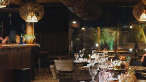 A restaurant with wicker chairs, a wooden table, and hanging light fixtures. - Villa Kandui Boutique Hotel (Maraú)
