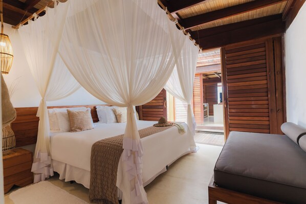 Un dormitorio con cama a dosel, cabecera de madera, mesitas de noche y vistas al exterior.