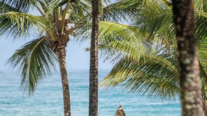 An outdoor seating area with wooden tables and wicker chairs, overlooking the ocean. - Villa Kandui Boutique Hotel (Maraú)