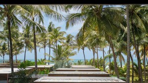 A resort with a view of the ocean, palm trees, and a series of wooden steps leading to a beach area. - Villa Kandui Boutique Hotel (Maraú)