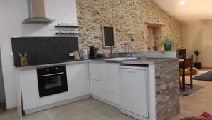 Eine moderne Küche mit weißen Schränken, einem eingebauten Backofen und einem Geschirrspüler. Eine Akzentwand aus Stein und ein kleines Fenster über der Spüle sind ebenfalls vorhanden.