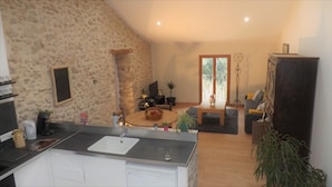 Eine Küche mit Spüle, ein Essbereich mit rundem Tisch und ein Wohnzimmer mit Sofa und Fernseher.