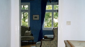 A room with a wooden floor, a blue wall, a chandelier, a chair, and a bed. - Hotel Schloss Sindlingen (Jettingen)
