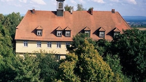 A large, multi-story building with a red-tiled roof, multiple windows, and a small tower-like structure on the roof. - Hotel Schloss Sindlingen (Jettingen)