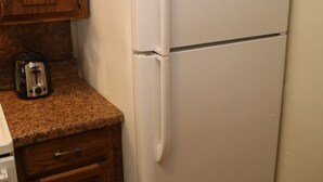 Eine Küche mit Holzausstattung, einem weißen Kühlschrank und einem Toaster auf der Arbeitsfläche.