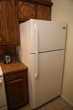 A kitchen with wooden cabinets, a white refrigerator, and a toaster on the countertop. - Spacious 2BR/1BA Stay Minutes from Fort Sill (Lawton)