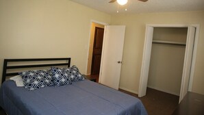 Ein Schlafzimmer mit einem Bett, einem Deckenventilator und einem Kleiderschrank.