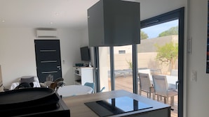 A modern kitchen with a dining area, large windows, and an outdoor patio. - Cala Rossa: MT **** charm + Quality / Price – Private heated pool-Air conditioning- WIFI (Lecci)