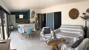 A modern living room with a sofa, coffee table, and dining area with chairs. - Cala Rossa: MT **** charm + Quality / Price – Private heated pool-Air conditioning- WIFI (Lecci)