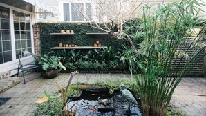 Un jardin avec un bassin, des plantes en pot et une statue.