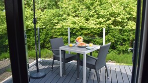 Un espace de restauration en plein air, avec une table et des chaises, entouré de verdure.