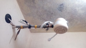 Un soffione doccia fissato al soffitto con un tubo flessibile e una manopola di controllo.