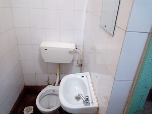 A small, basic bathroom with a toilet, bidet, and sink. - Tarino Bar And Lodging (Kitengela)