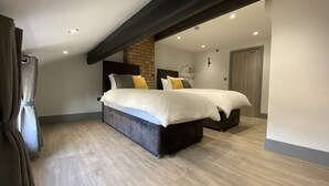 A modern bedroom with a large bed, a stone accent wall, and a wooden floor. - 6Adelphi (Preston)