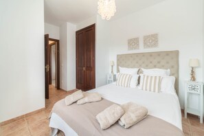 A bedroom with a large bed, two bedside tables, a wooden door, and a chandelier. - SON RUBI Finca for 7 in Selva with Pool (Selva)