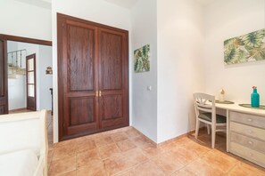 A hallway with a wooden double door, a chair, a small table with a bottle, and a wall with a leaf pattern. - SON RUBI Finca for 7 in Selva with Pool (Selva)