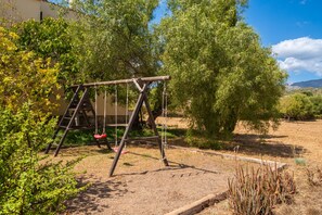 A wooden swing set in a garden with trees and dry grass. - SON RUBI Finca for 7 in Selva with Pool (Selva)