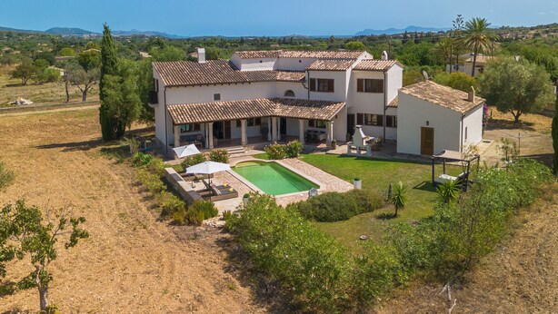 Une maison à deux étages avec une piscine, entourée d’un jardin et offrant une vue sur la mer.