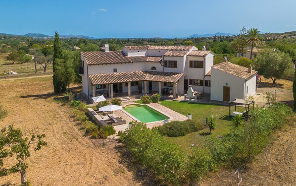 Une maison à deux étages avec une piscine, entourée d’un jardin et offrant une vue sur la mer.