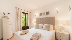 Une chambre d’hôtel avec un grand lit, deux tables de chevet avec des lampes, une armoire et une fenêtre avec des rideaux.