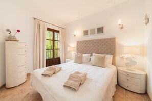 Une chambre d’hôtel avec un grand lit, deux tables de chevet avec des lampes, une armoire et une fenêtre avec des rideaux.