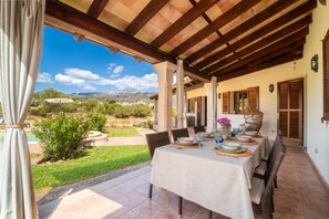 An outdoor dining area with a table set for four, overlooking a garden and a mountainous landscape. - SON RUBI Finca for 7 in Selva with Pool (Selva)