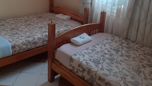 A room with two wooden beds, each with patterned bedding and pillows. - Ukombozi Retreat & Conference Centre - Hostel (Thika)