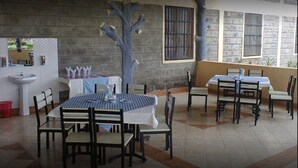 A dining area with tables and chairs, a sink, and a decorative tree sculpture. - Ukombozi Retreat & Conference Centre - Hostel (Thika)