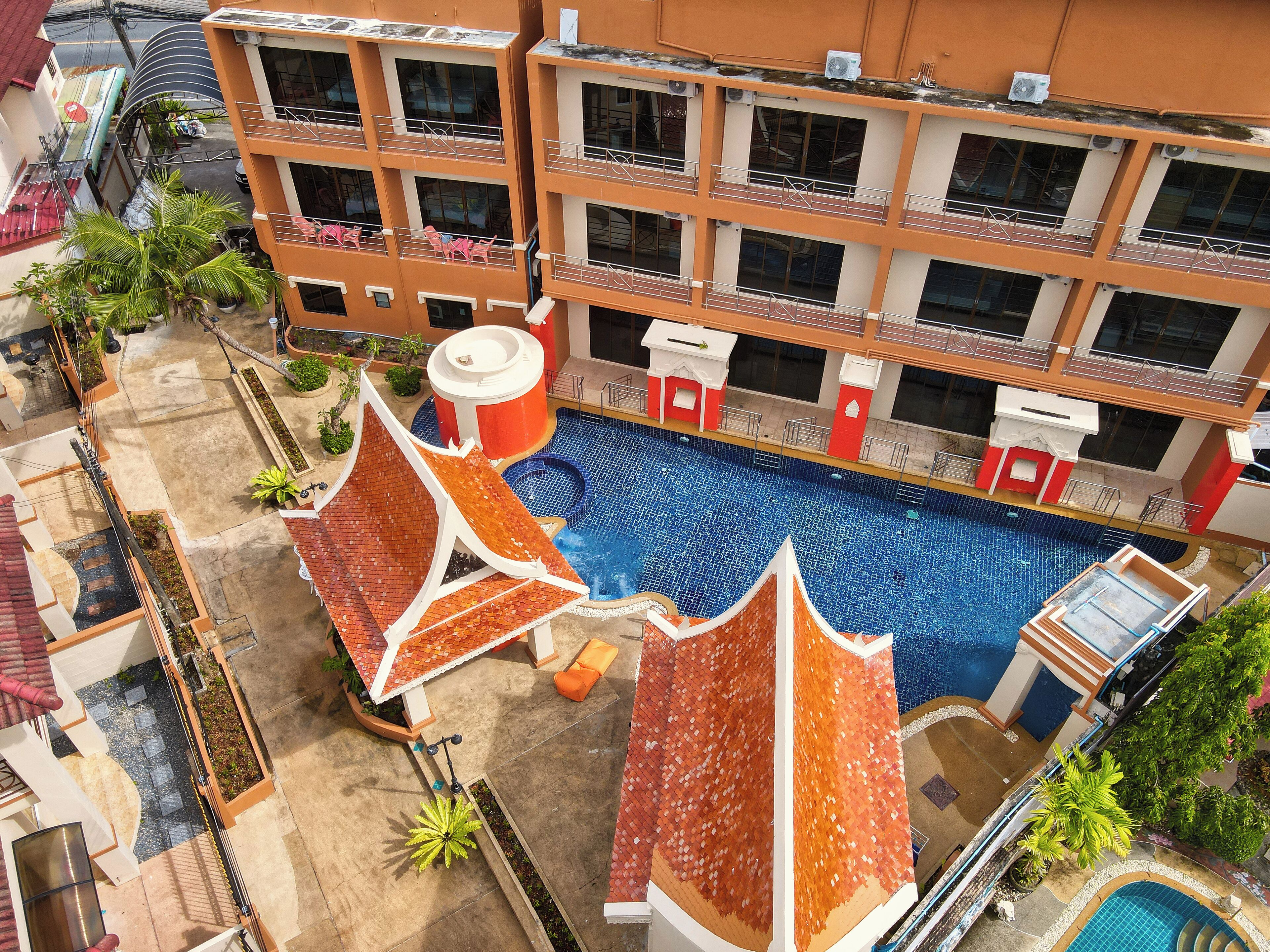 A multi-story hotel with a rooftop pool area, including a large swimming pool and a smaller hot tub.