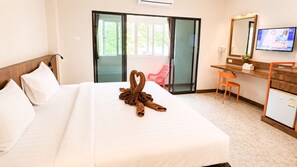 Een hotelkamer met een bed, een bureau, een stoel, een televisie en een schuifdeur.
