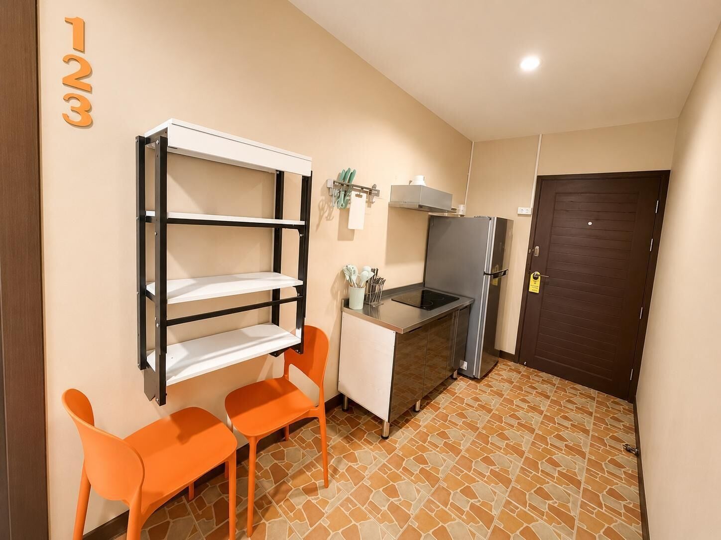 A compact kitchen with a built-in stove, a refrigerator, and a small dining area with two chairs.