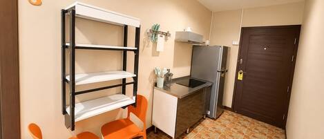 A compact kitchen with a built-in stove, a refrigerator, and a small dining area with two chairs.