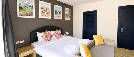 A hotel room with a bed, bedside tables, a sofa, and artwork on the walls.