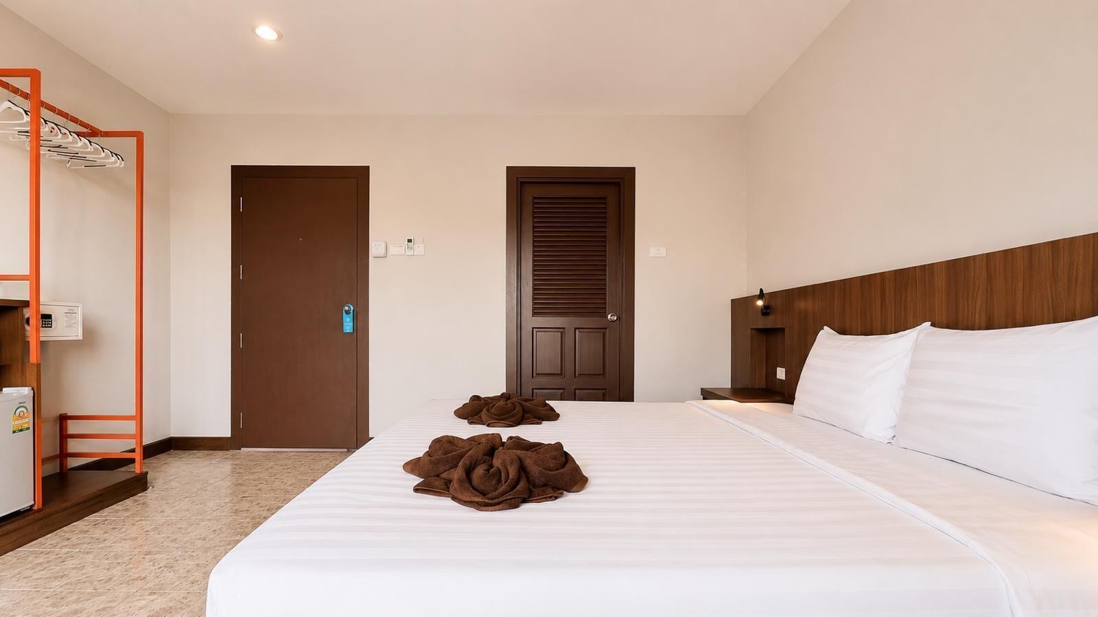 A hotel room with a bed, a wardrobe, a mirror, and a small table.