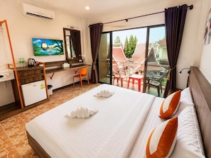 Ein Hotelzimmer mit Bett, Schreibtisch, Stuhl, Fernseher und einem Balkon mit Blick.