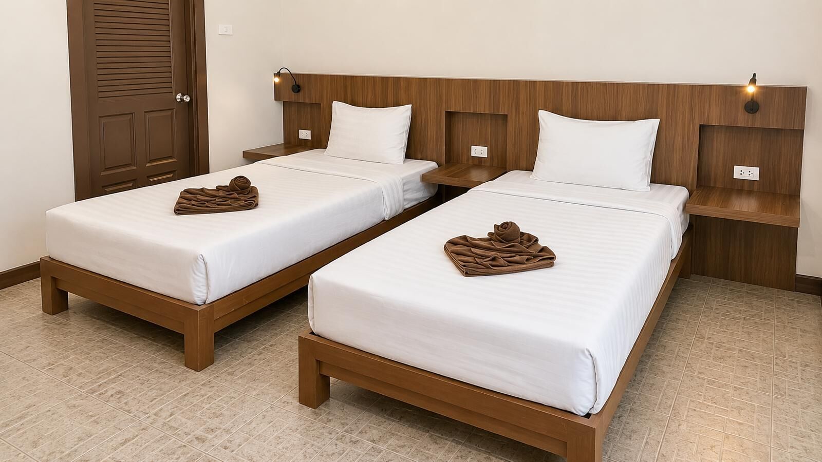 Dos camas individuales con cabeceros de madera, ropa blanca y un marco de madera, junto a una puerta marrón.