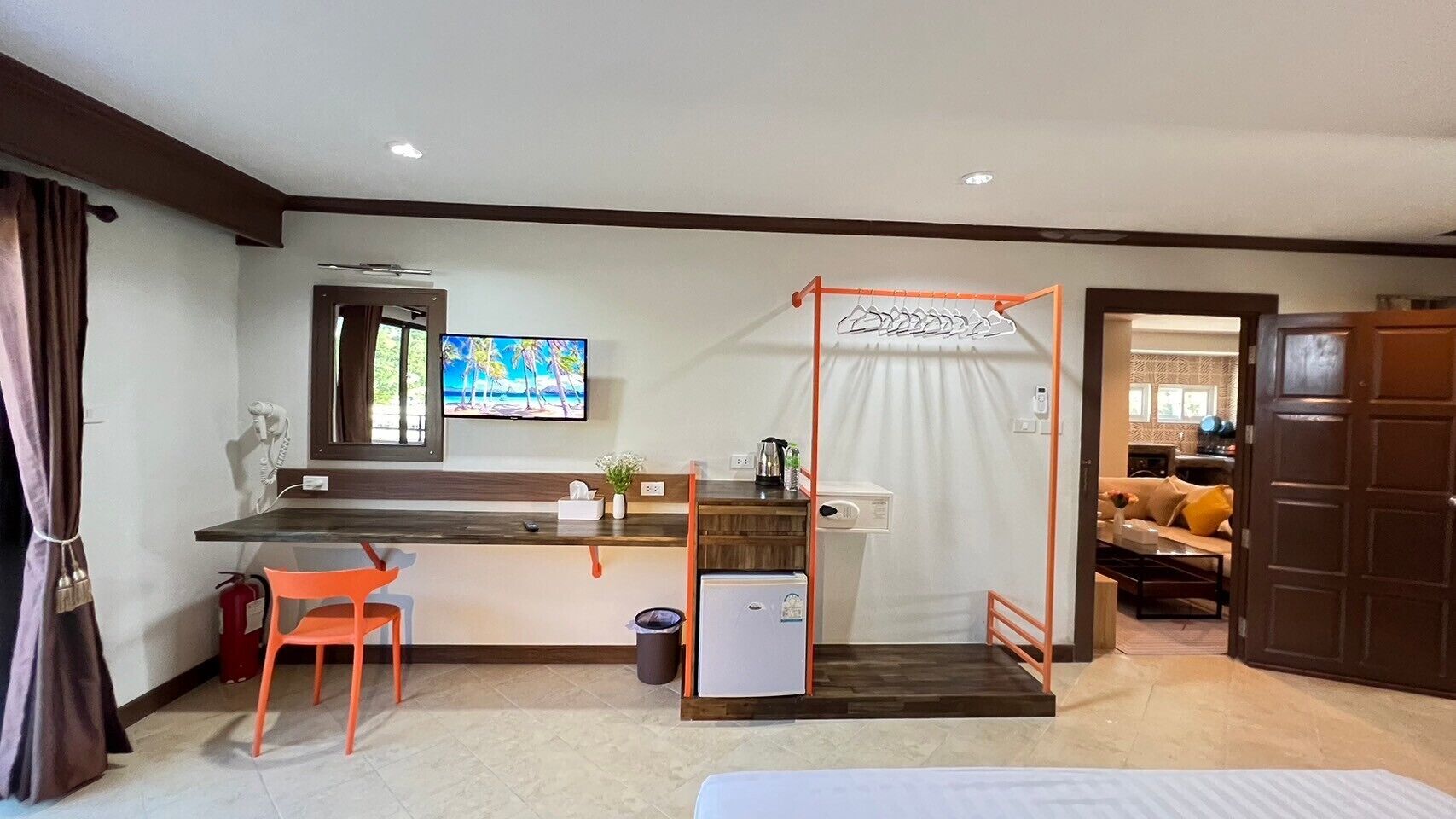 Une chambre d’hôtel équipée d’une kitchenette, d’une télévision, d’une petite table avec une chaise et d’une porte donnant sur un espace de vie.