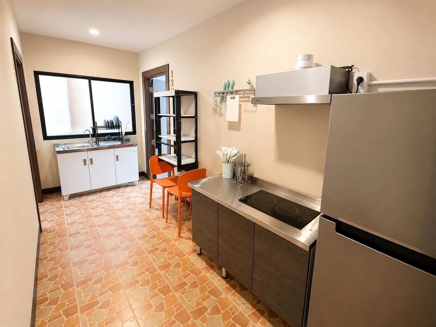 A compact kitchen with a built-in stove, a refrigerator, and a window with a city view.