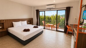 A hotel room with a bed, a desk, a chair, and a balcony with a view. - My Friend's House (Karon)