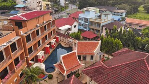 A multi-story hotel with a rooftop pool, balconies, and a mix of traditional and modern architecture. - My Friend's House (Karon)