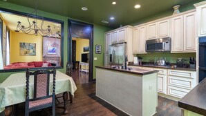 A kitchen with white cabinets, a stainless steel refrigerator, a microwave, and a sink. There is a dining area with a table and chairs. - Easy access to Taylor Swift, Broadway, CMAs & more (Nashville)